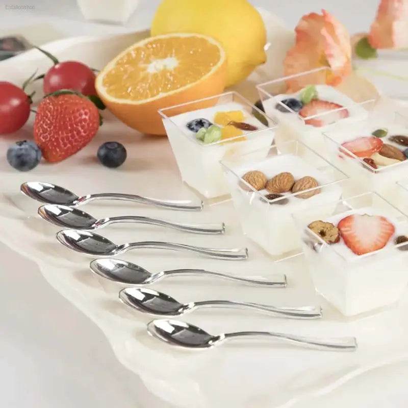 Dessert cups with fruit and spoons.