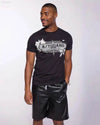 Man in black t-shirt and leather shorts.
