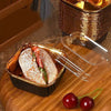 Sandwich in a black and gold container with a clear lid.