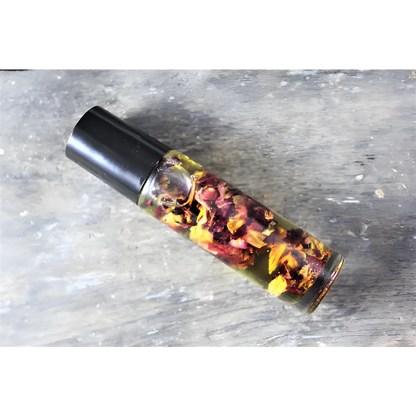 Glass bottle with black cap filled with organic essential oil and flower petals