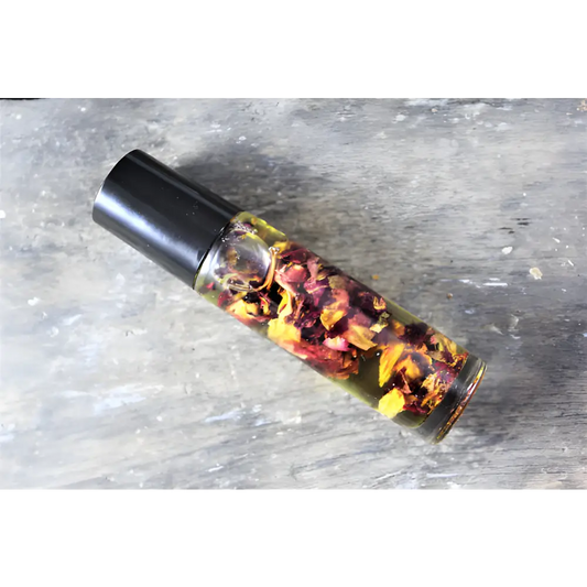 Glass bottle with black cap filled with organic essential oil and flower petals