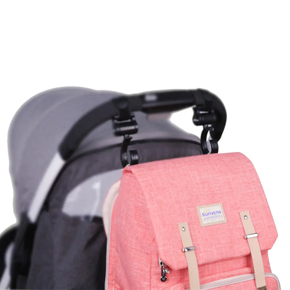 Pink Canvas Diaper Bag Travel Backpack hanging from stroller hooks with insulated bottle holders