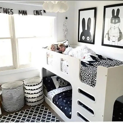 White bunk bed with black and white bedding, perfect for a clothing storage basket