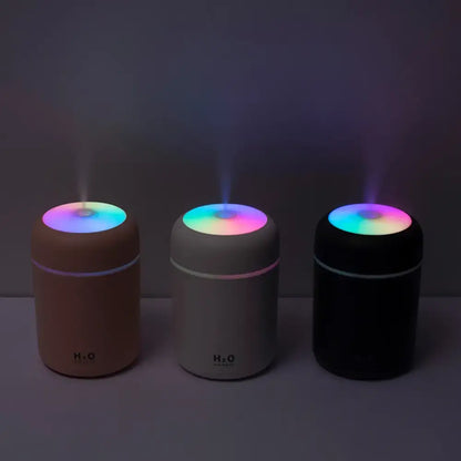 Three colorful portable air humidifiers glowing as essential oil diffusers