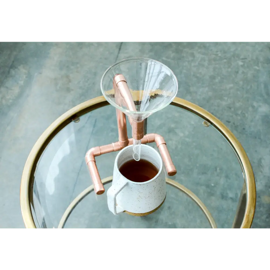 Copper coffee pour-over stand with glass funnel and speckled mug as functional art