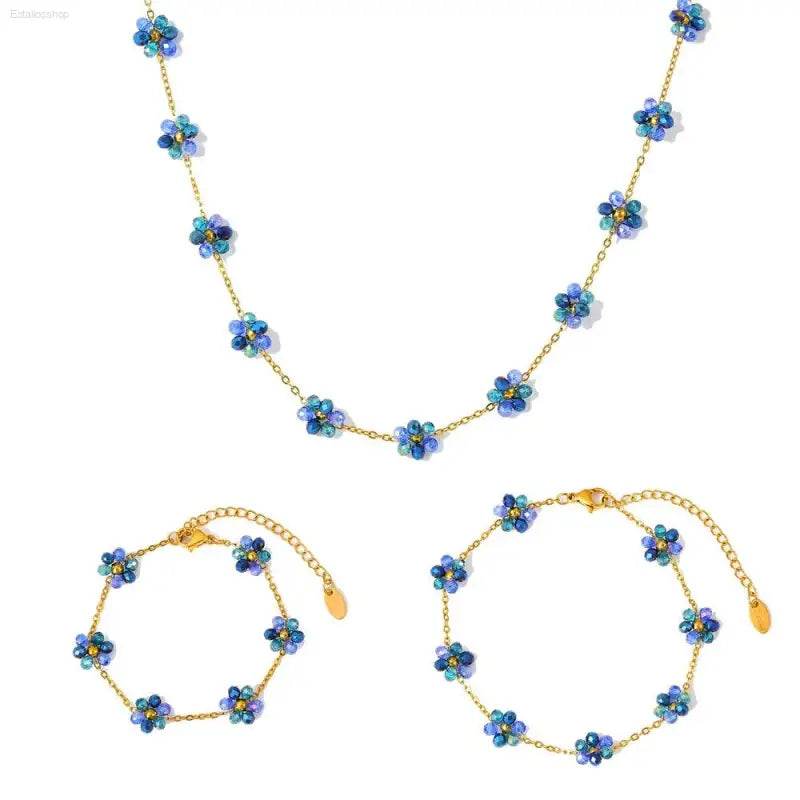 Gold chain necklace and bracelets with blue flower beads.