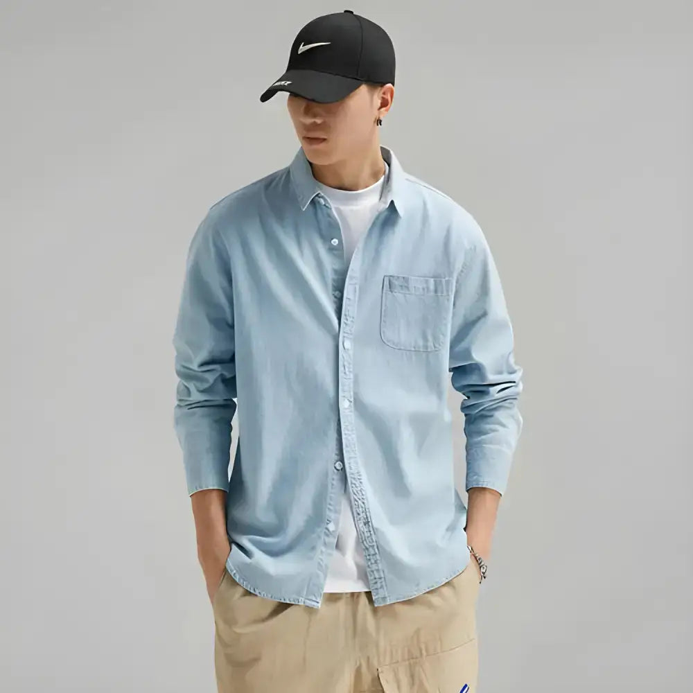 Man in light blue denim shirt with black baseball cap, showcasing stylish combo