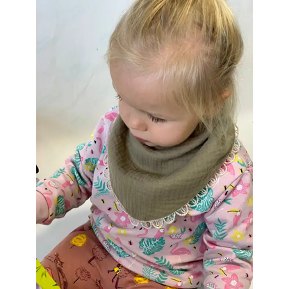 Toddler rocking a cool khaki double-sided muslin scarf-bib with a fun patterned shirt