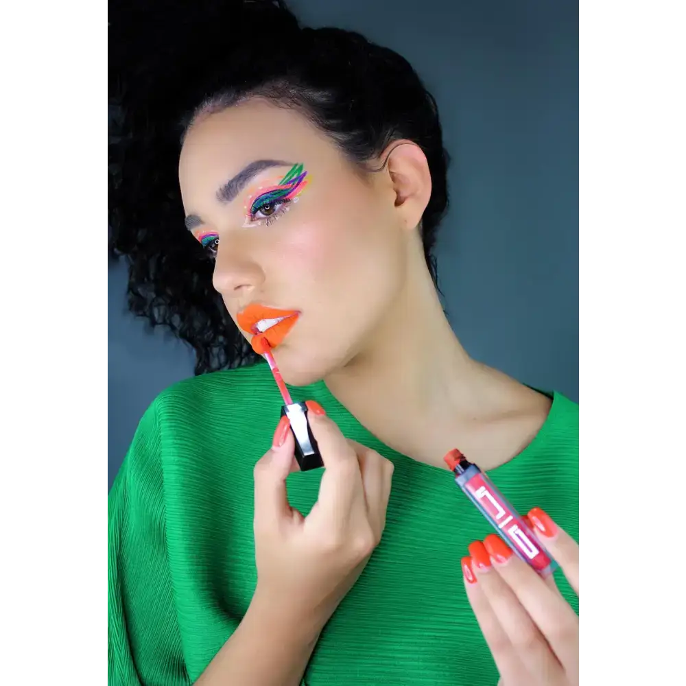 Woman applying bold orange lip with edgy deep eyeliner for a stunning look