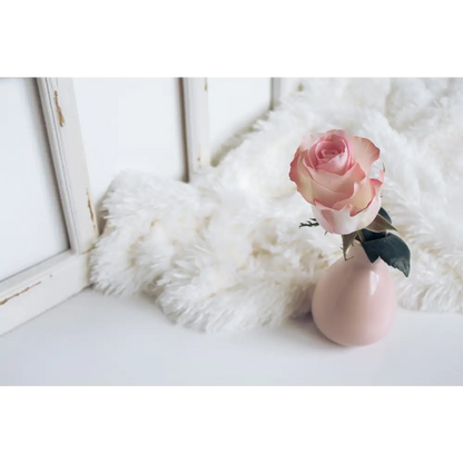 Pink rose in a vase on a fluffy lambskin rug, adding a touch of elegance