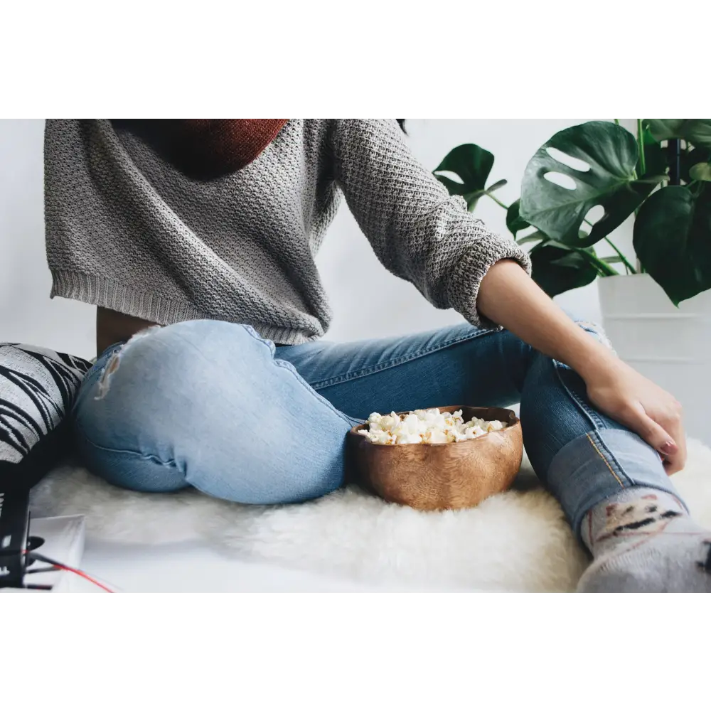 Wooden bowl filled with popcorn on a cozy Fluffy Lambskin Rug for a perfect movie night