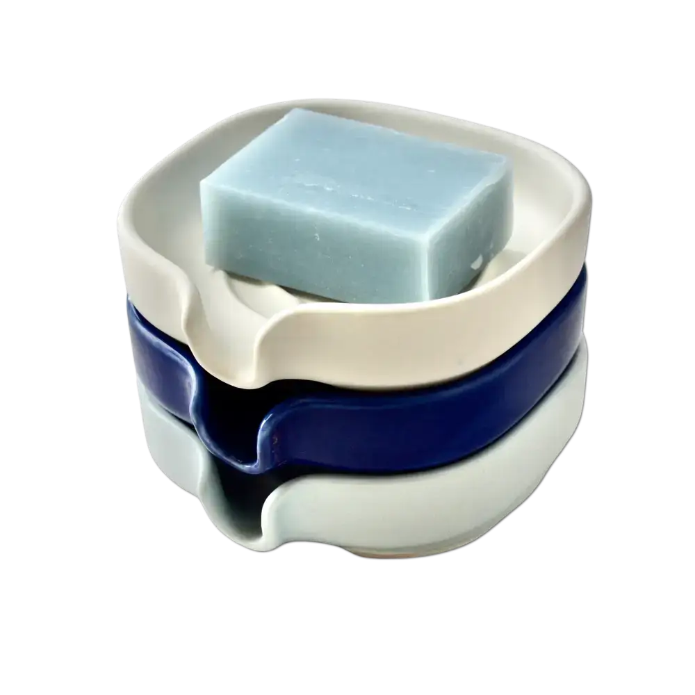 Stacked self-draining porcelain soap dishes in glossy cobalt blue with soap on display