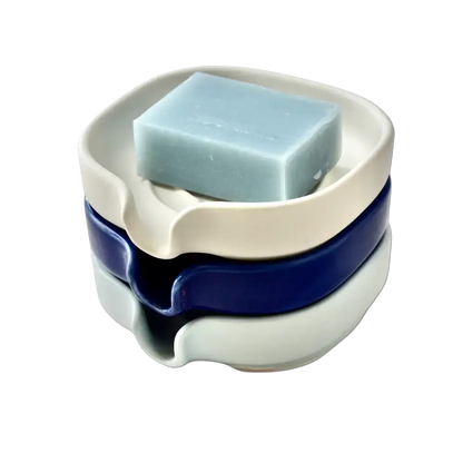 Stacked self-draining porcelain soap dishes in glossy cobalt blue with soap on display