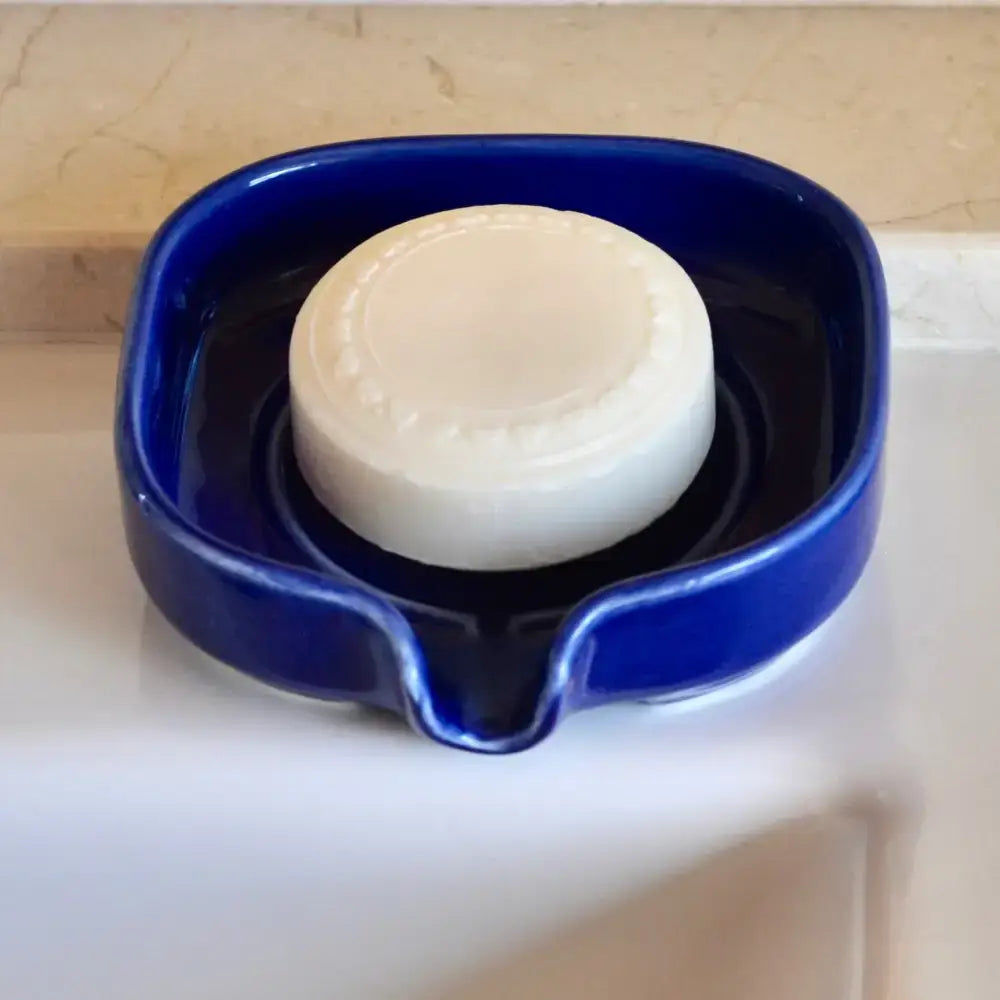 Round white soap in a glossy cobalt blue self-draining porcelain soap dish