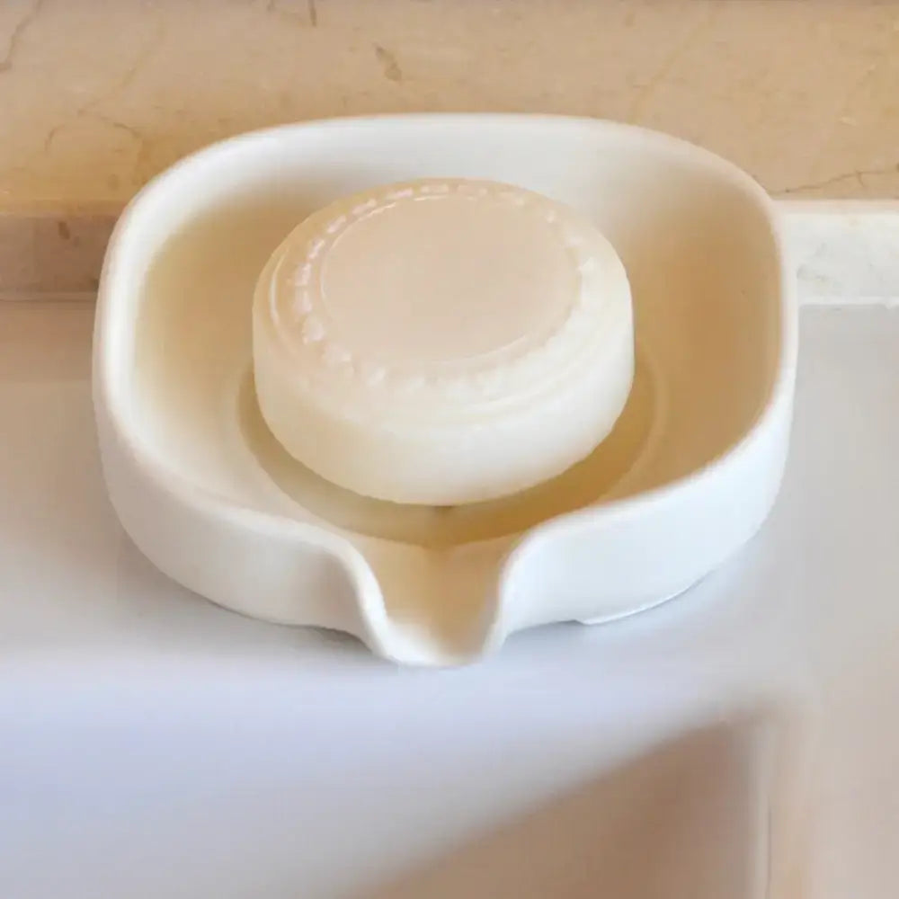 Round bar of soap in a Glossy Cobalt Blue Self-Draining Porcelain Soap Dish