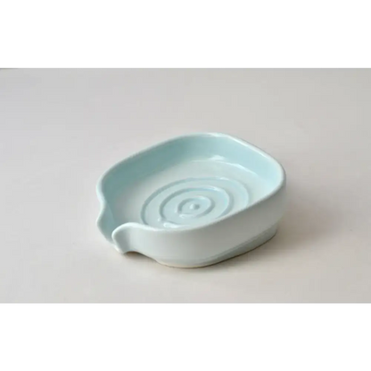 Light blue ceramic spoon rest next to a Glossy Cobalt Blue Self-Draining Soap Dish