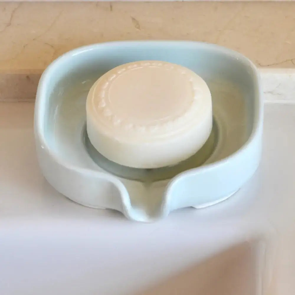 Round bar of soap in a glossy cobalt blue self-draining porcelain soap dish