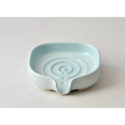 Light blue ceramic spoon rest next to a Glossy Cobalt Blue Self-Draining Soap Dish