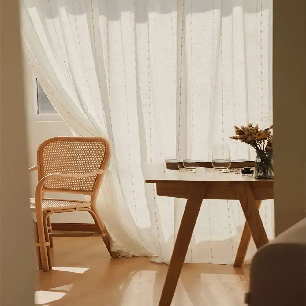 Wicker-backed chair with Linen Sheer Curtains showcasing elegant embroidered ball design