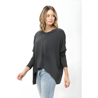 Woman wearing a gray dolman sleeve oversized knit tunic blouse for a stylish look