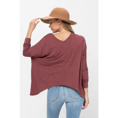 Woman in a maroon knit tunic blouse with dolman sleeves and a stylish brown hat