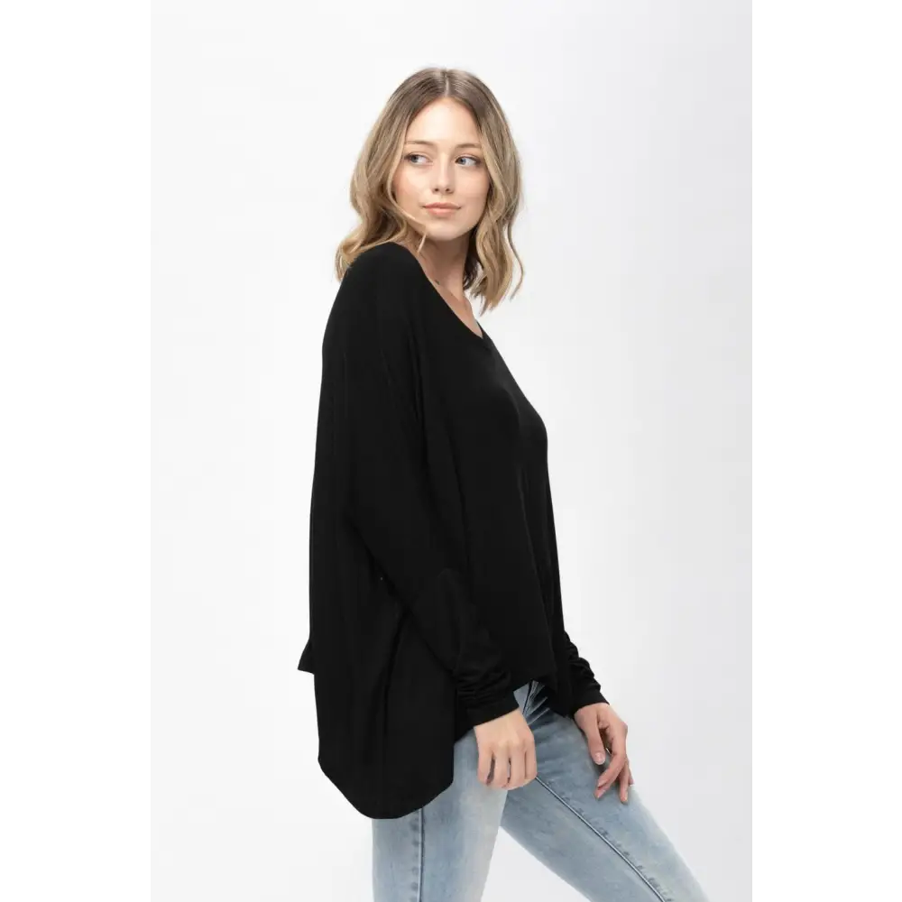 Woman wearing a black dolman sleeve oversized knit tunic blouse for casual style