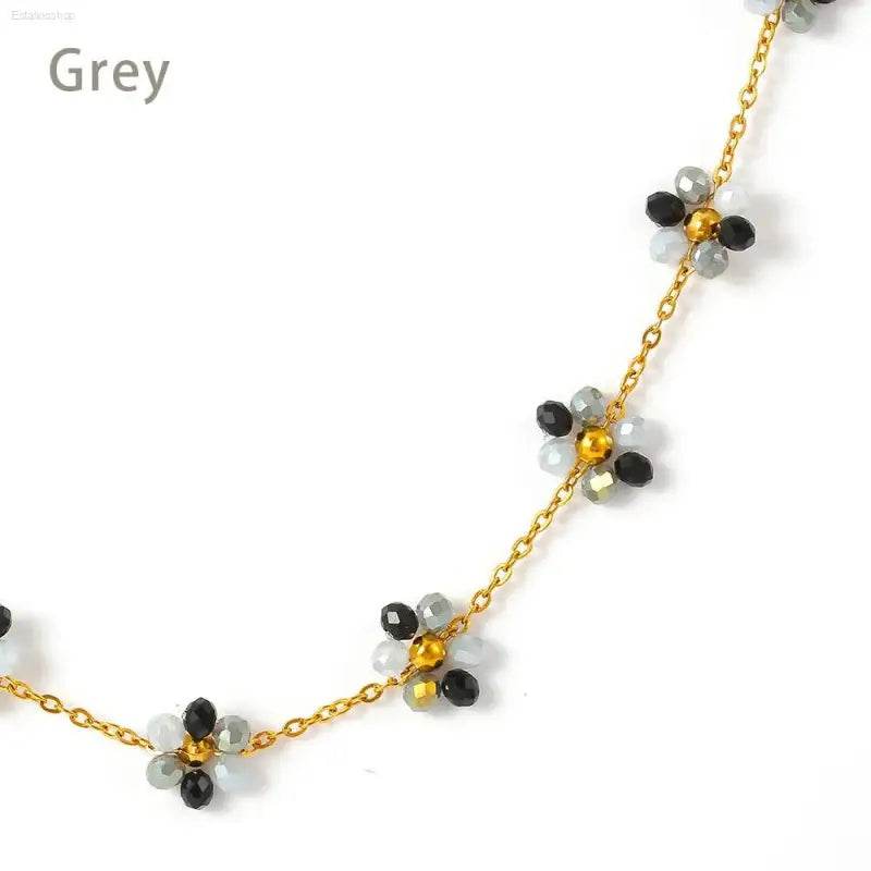 Gold chain necklace with beaded flower accents.