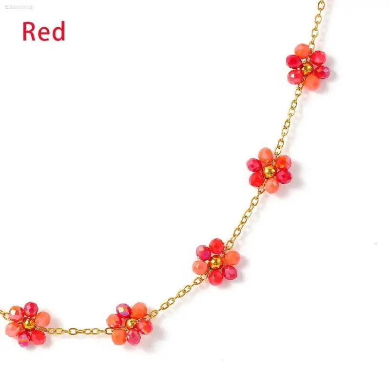 Gold chain necklace with red and orange beaded flowers.