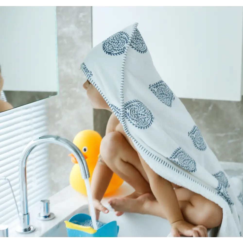 Child in a Paisley Print Hooded Towel building a towel fort and having fun with water