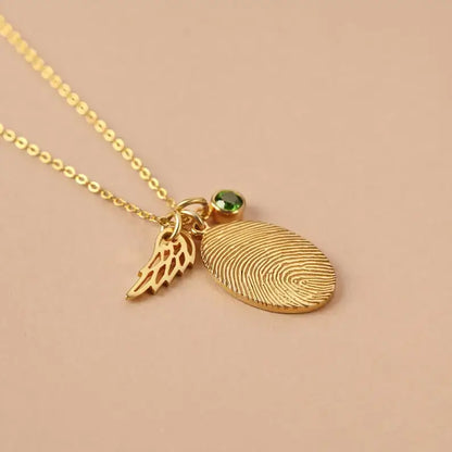 Gold fingerprint necklace with a wing charm and green gemstone in rose gold