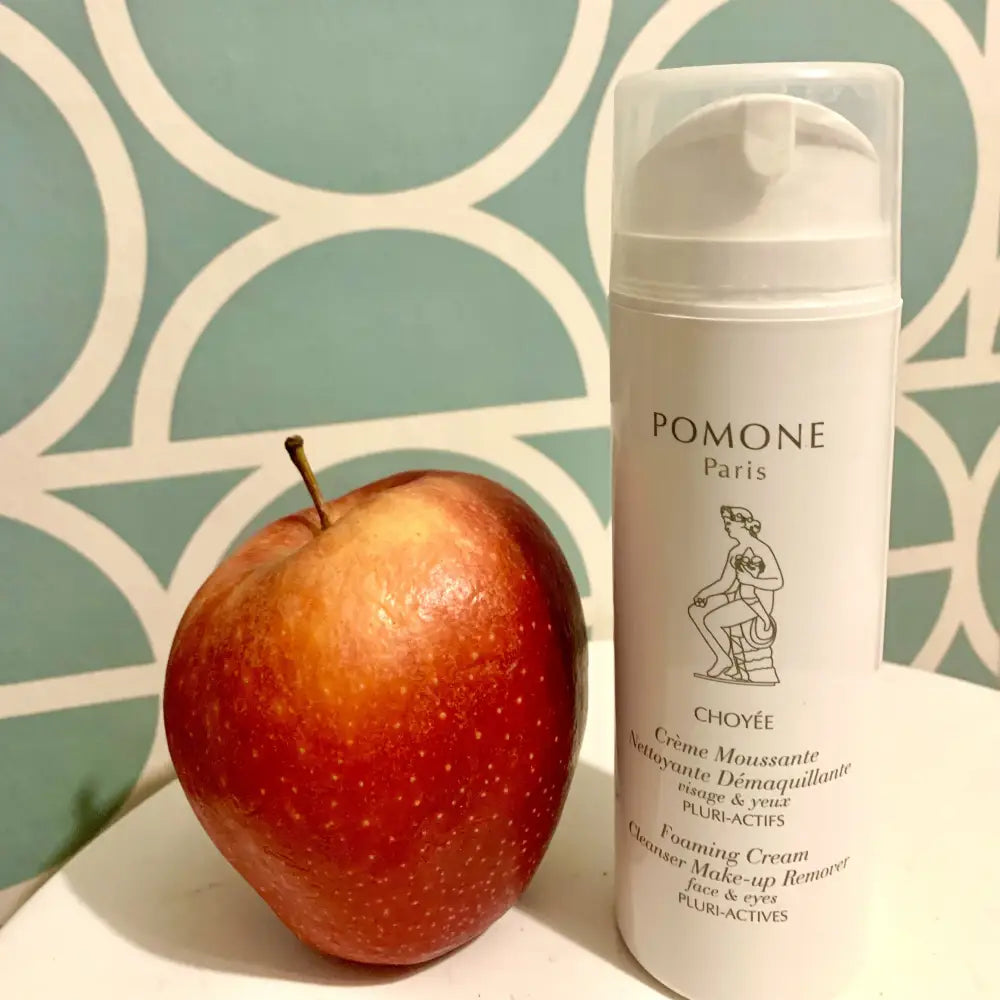 Red apple and white bottle showcasing Pomone Paris Apple Pluri-Actives Cleanser