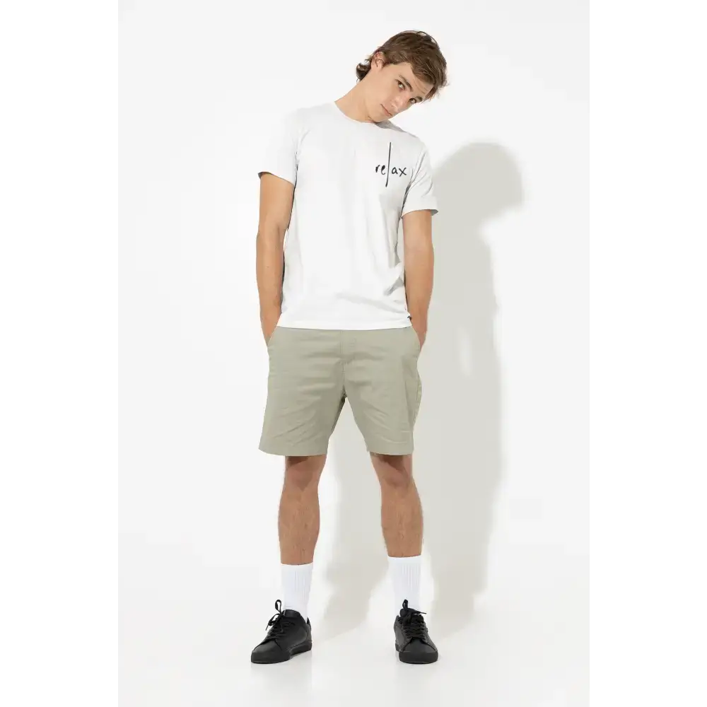 Man in a white sold classic unisex t-shirt and khaki shorts showcasing Swedish attitude