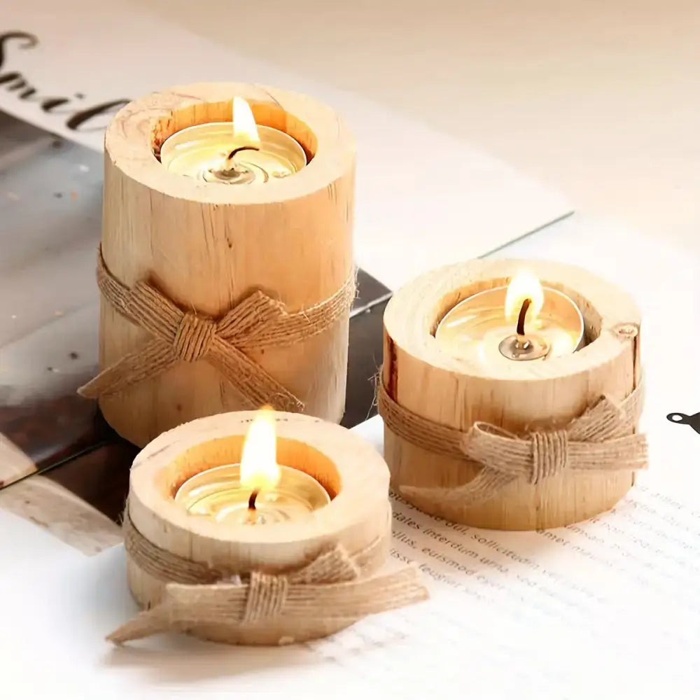 Three elegant wooden cylindrical candlesticks with lit tea lights in a chic set