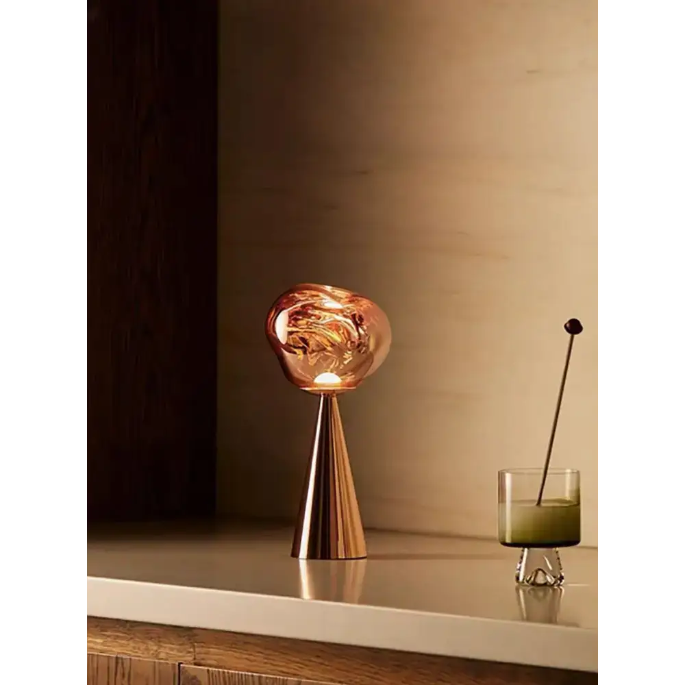 Sculptural modern table lamp featuring a stylish copper-colored glass design