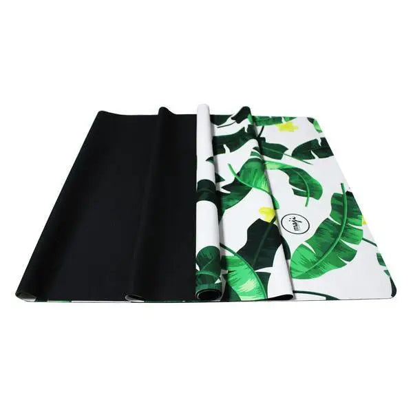 Partially rolled Tropical Rubber Travel Yoga Mat with a vibrant banana leaf pattern