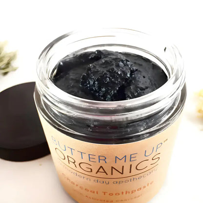 Open jar of Unleash Hollywood Smile Organic Activated Charcoal toothpaste with coconut oil