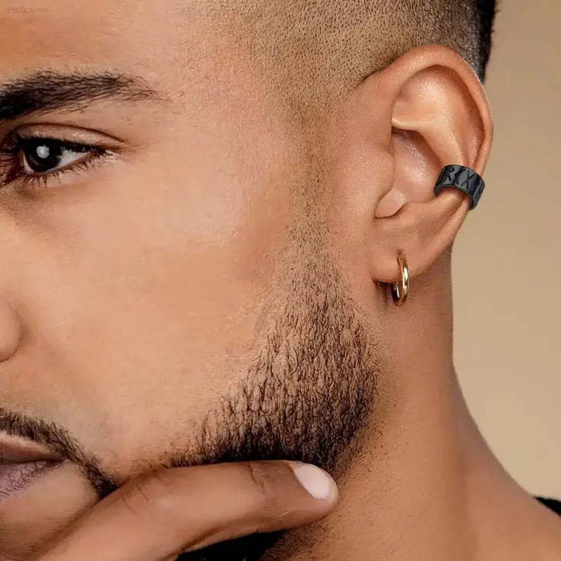 Man’s ear with black studded cuff and gold hoop earring.