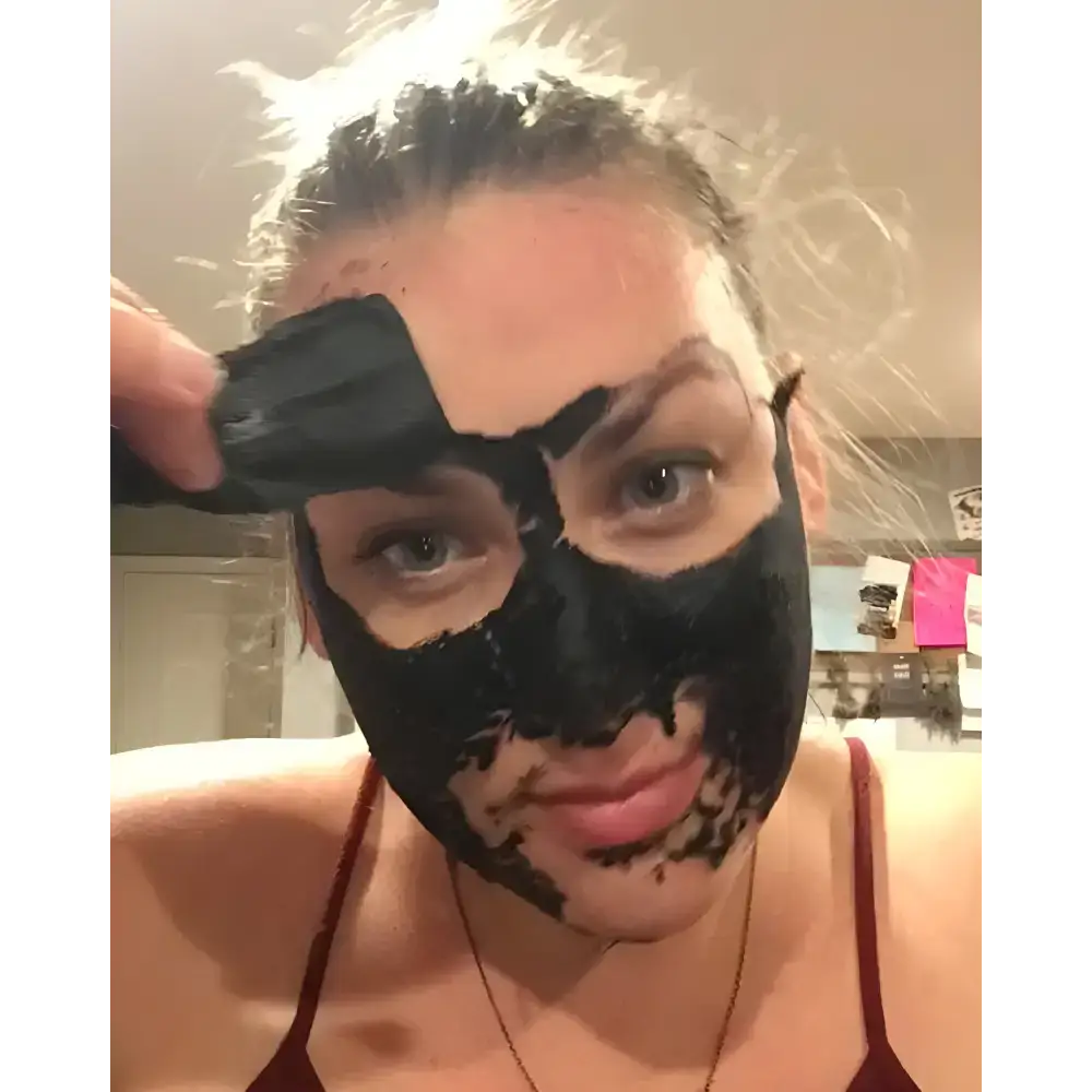 Woman removing black Vegan Activated Charcoal Peel for glowing skin